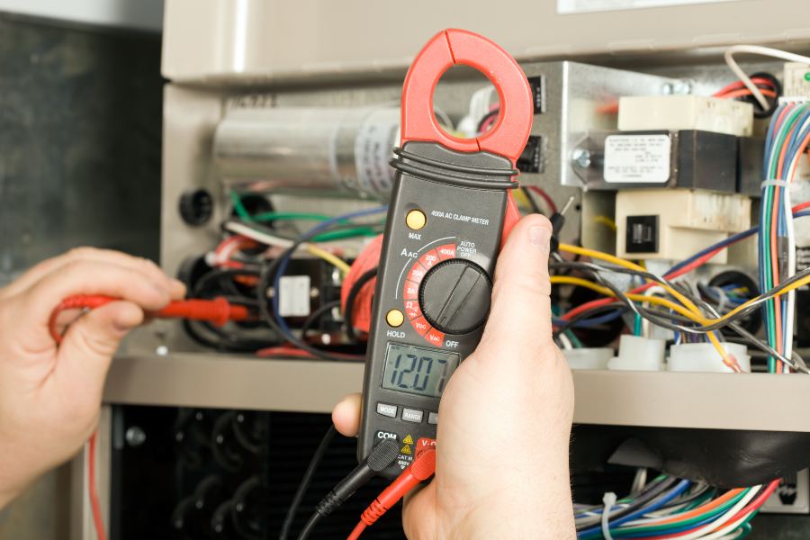 A person in Glendora, CA, using a multimeter to measure an electrical circuit