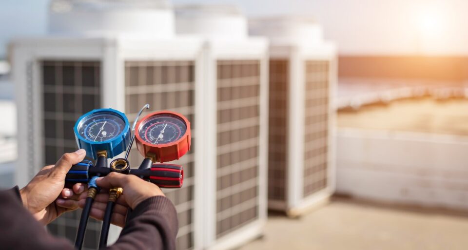 A man in Glendora, CA, inspecting a heat pump with a gauge in hand